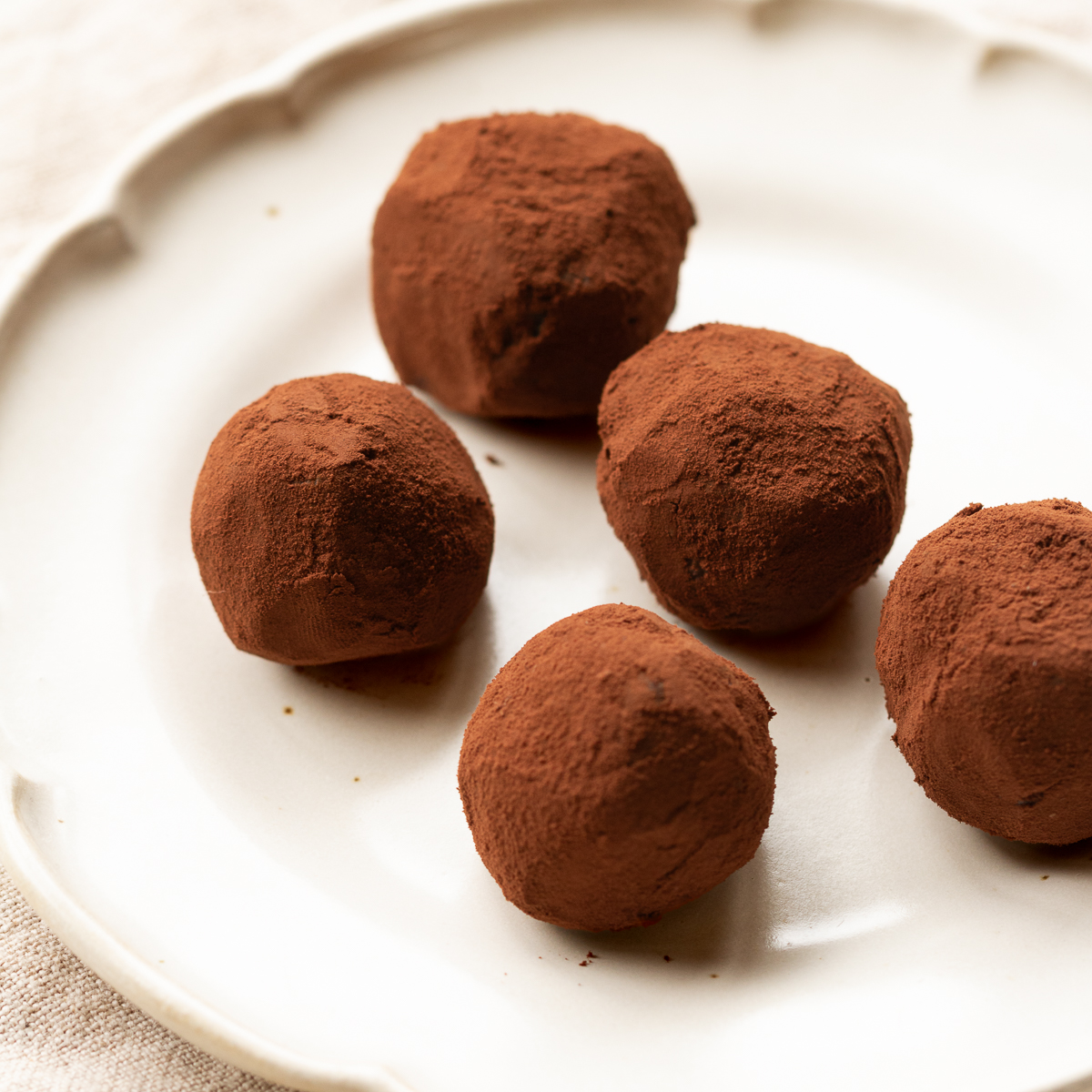 Vegan nama chocolate truffles dusted with cocoa powder on a plate. Vegan adzuki bean dessert.