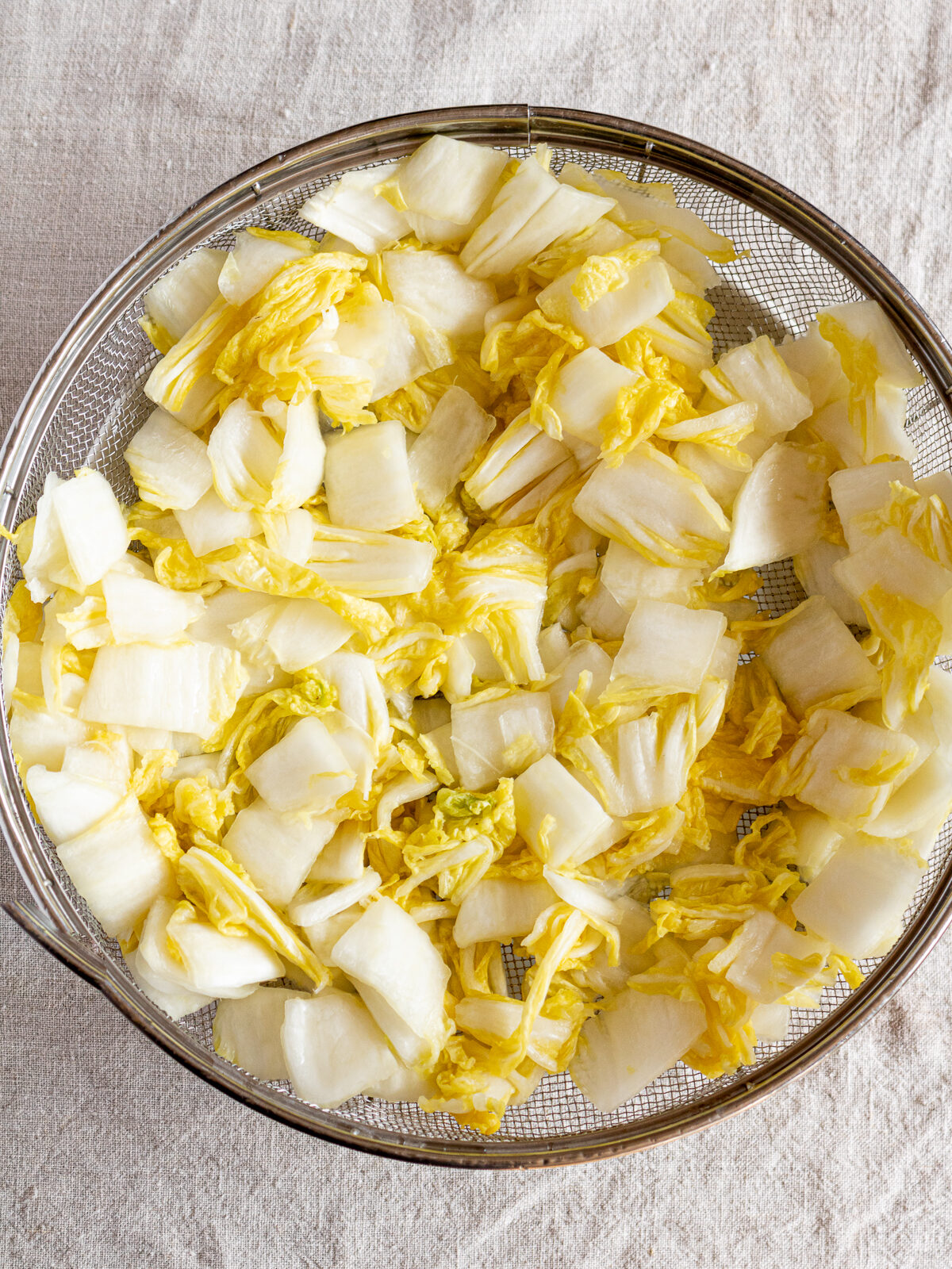 Salted napa cabbage draining in a colander