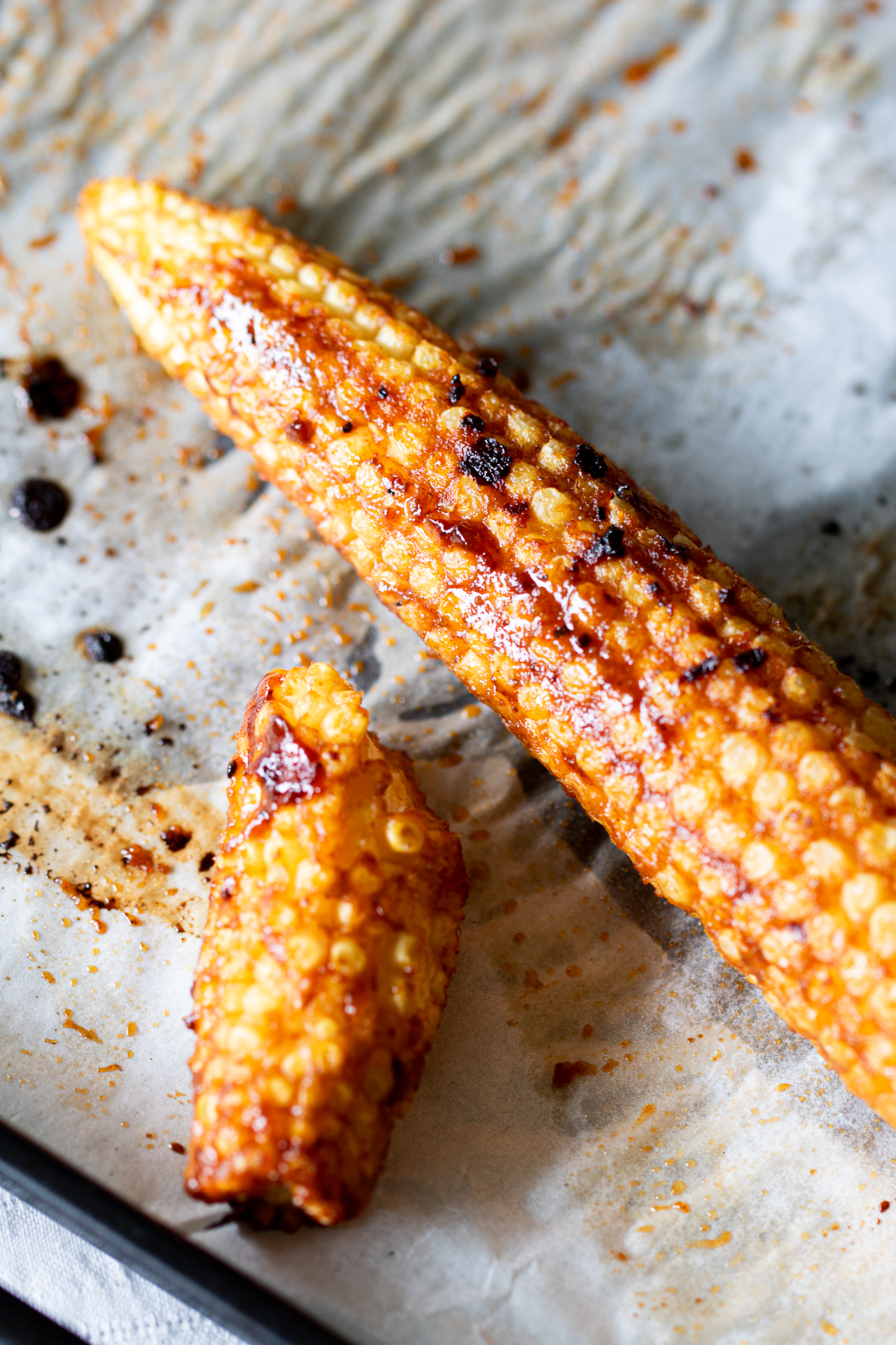 Oven-roasted baby corn with spicy BBQ marinade on parchment paper