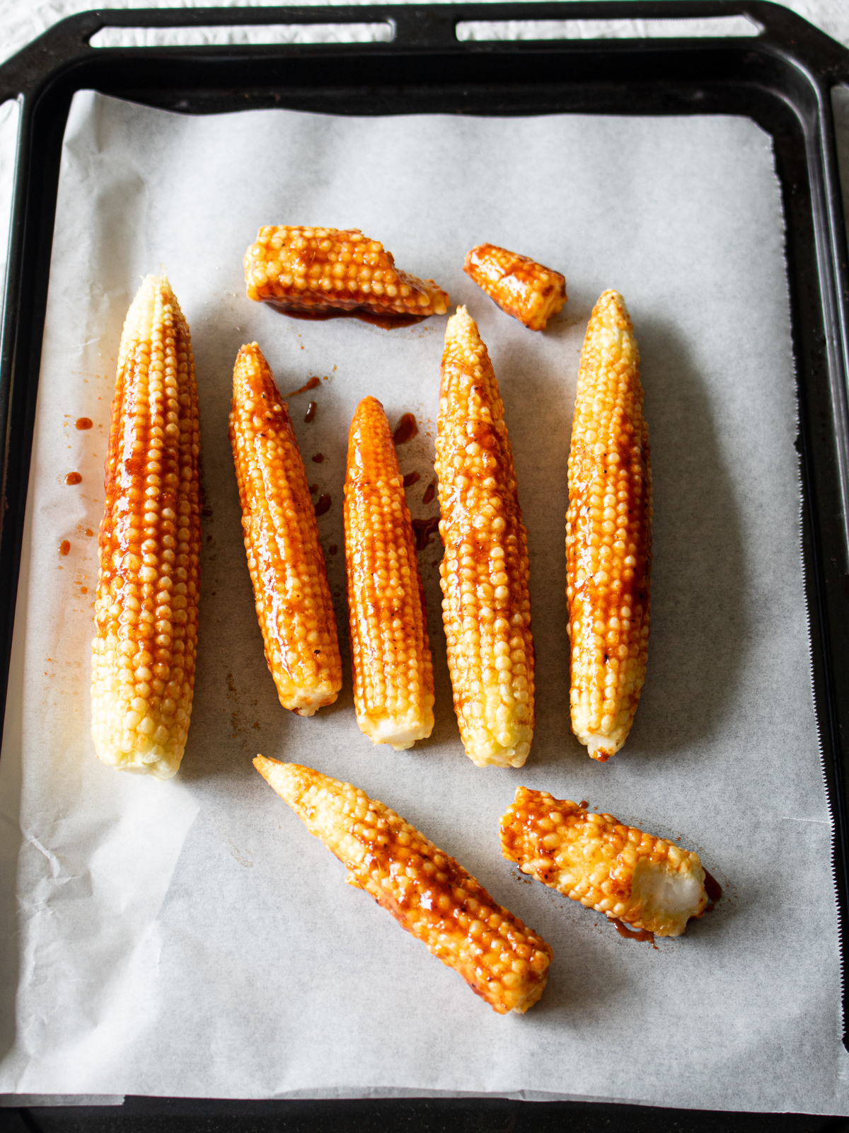Marinated young corn skewers ready to be baked