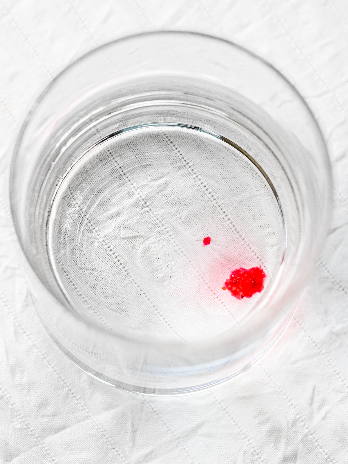A glass of water with a drop of jam