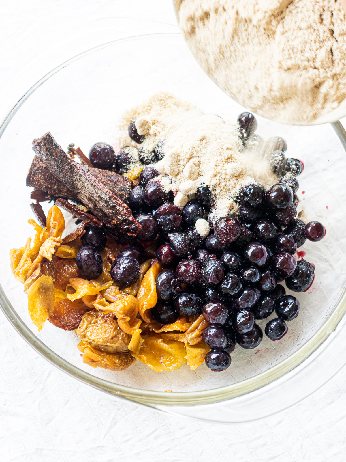 Ingredients for blackcurrant-style blueberry-plum jam are dusted with sugar.