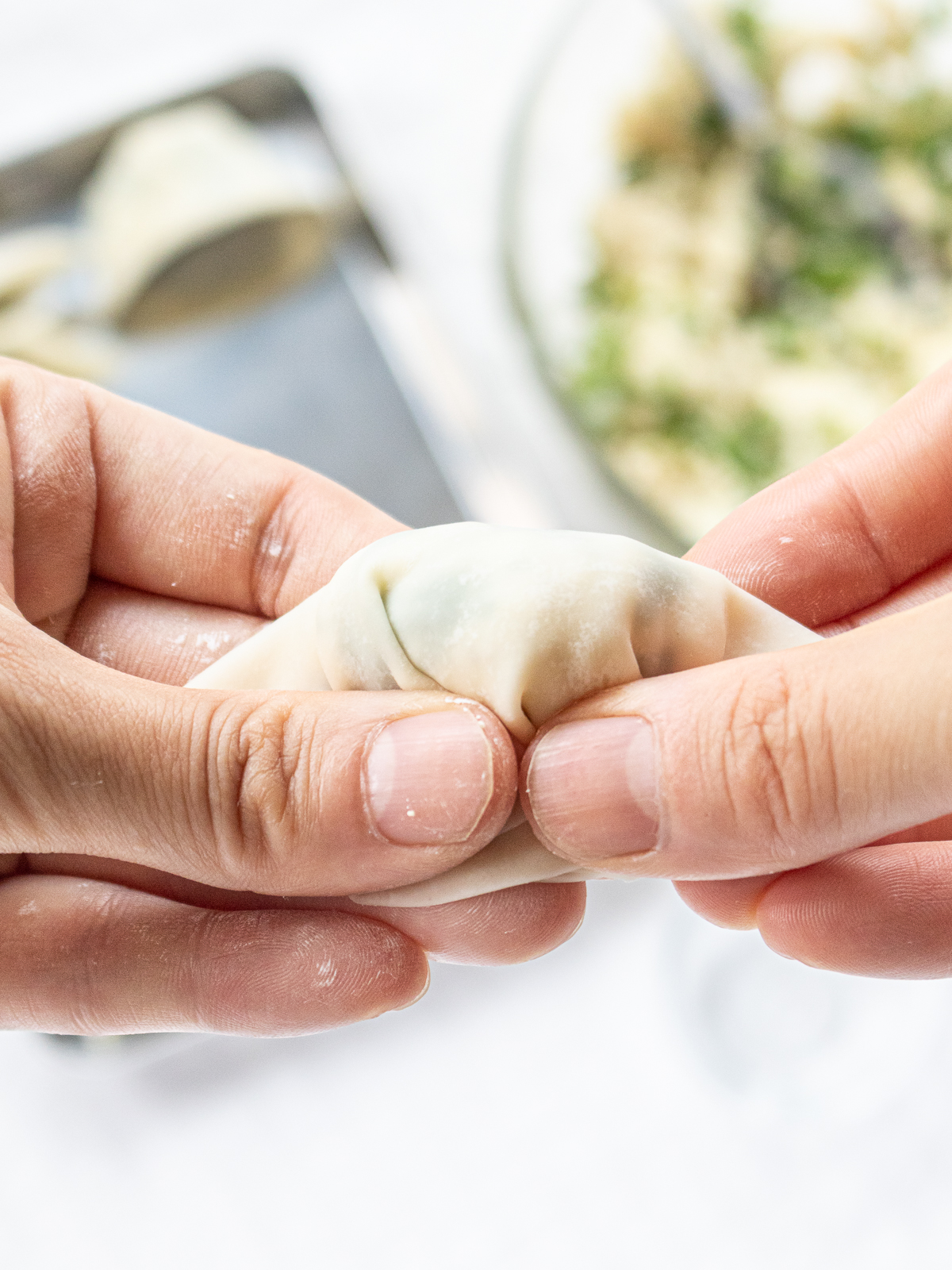 The dumplings are being wrapped so that the ingredients and skin adhere to each other.