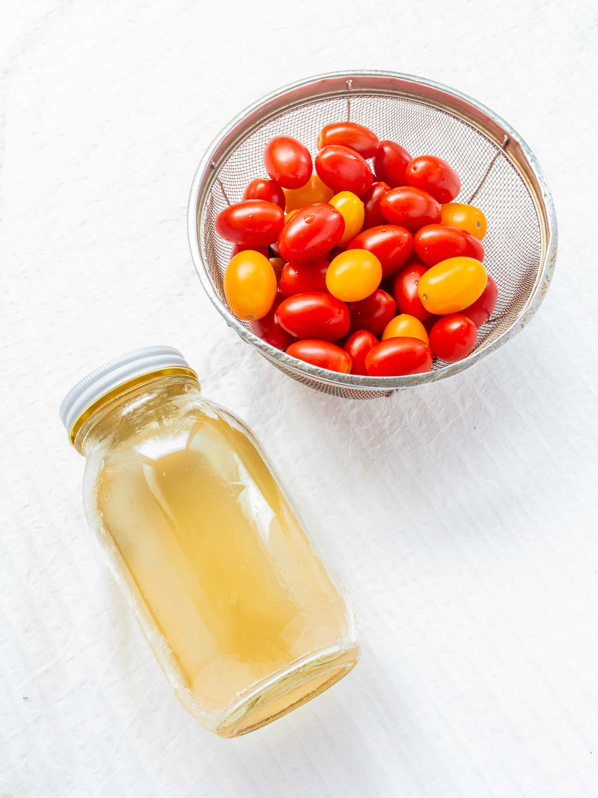 Fresh Cherry Tomatoes in a Colander and a Jar of Homemade Ume Syrup – Ingredients for Vegan Compote