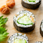 Ume shiso cucumber sushi rolls neatly arranged on a cutting board, showing the pink ume paste and green shiso