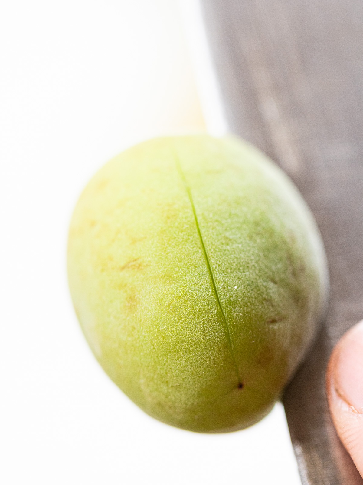Green plums with knife cuts