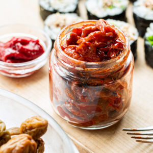 Maesil jangajji in a glass jar with homemade vegan kimbap using pickled plums