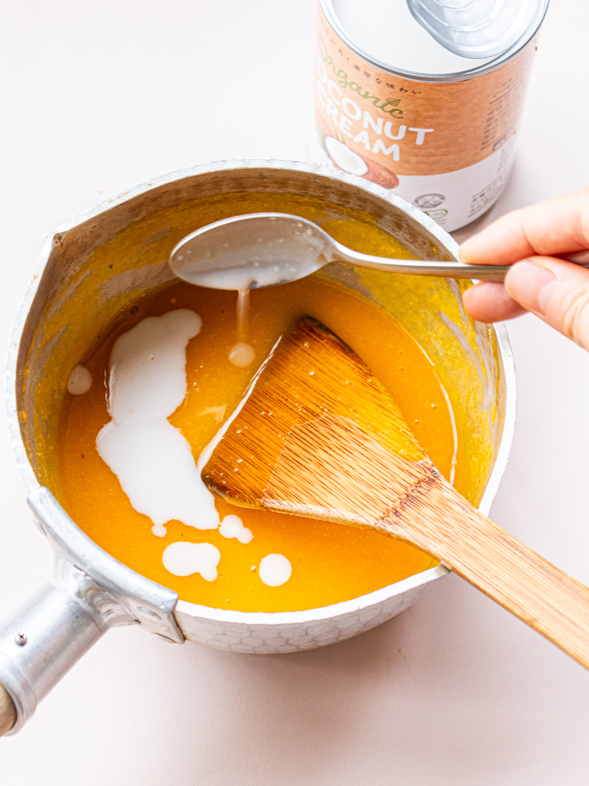 Adding coconut milk to warm pumpkin porridge — final step in vegan dessert prep