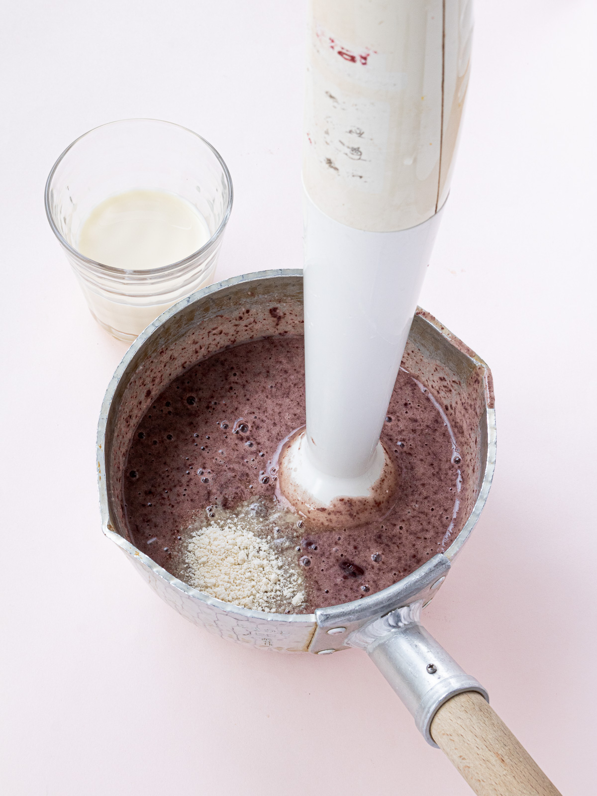 Blending adzuki beans, glutinous rice porridge, and sugar in a pot with an immersion blender