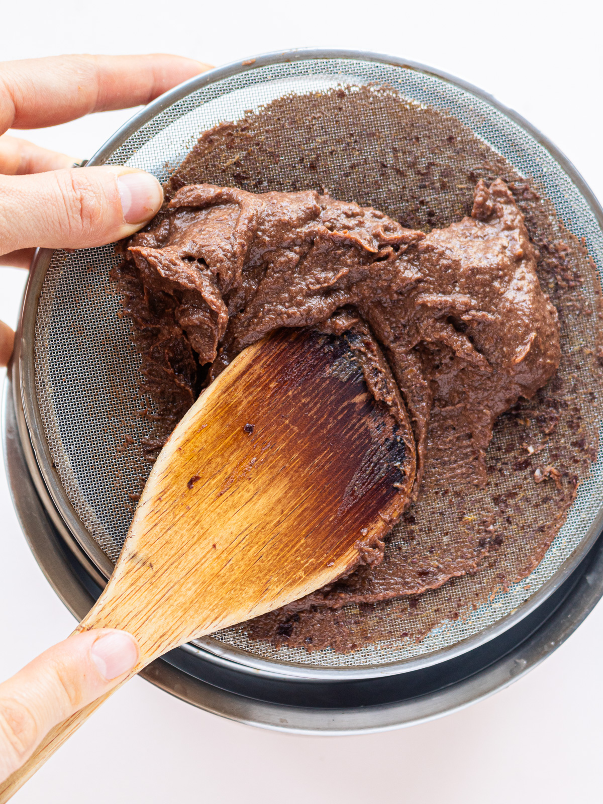 straining adzuki bean chocolate frosting through a sieve for a smoother texture