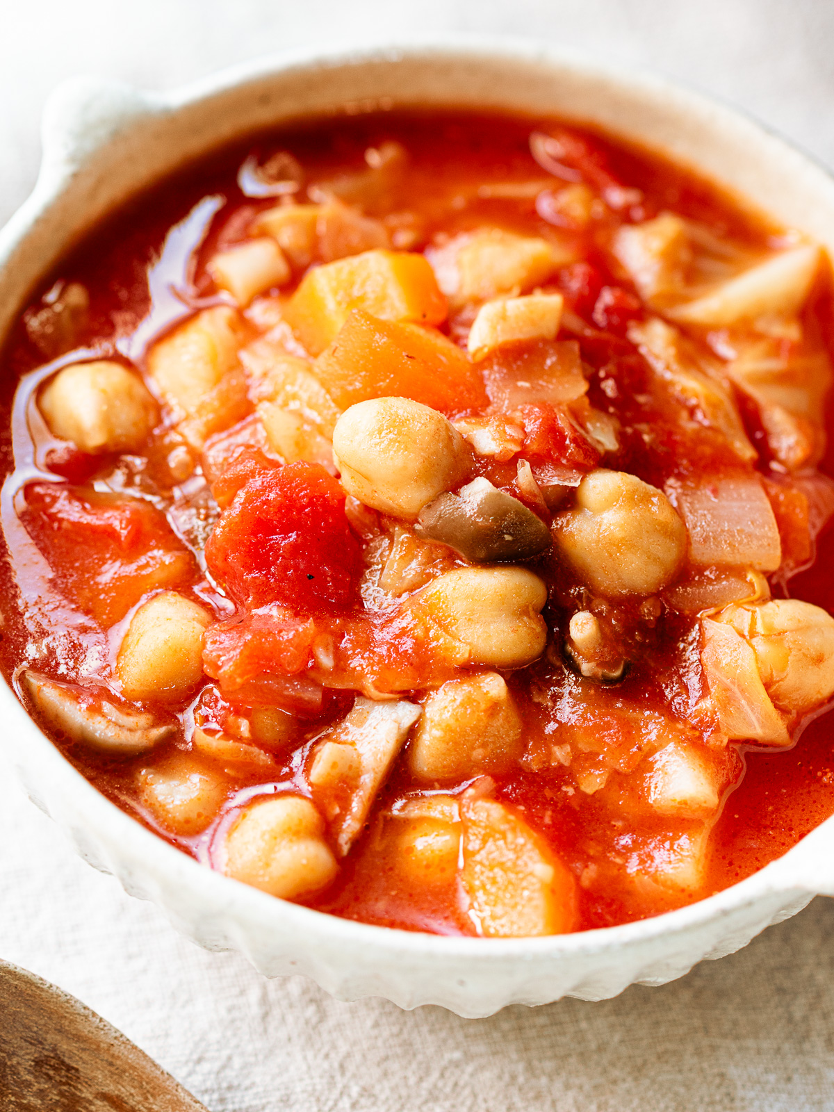 A brightly colored bowl of chickpea minestrone (vegan pork bean style) with lots of veggies.