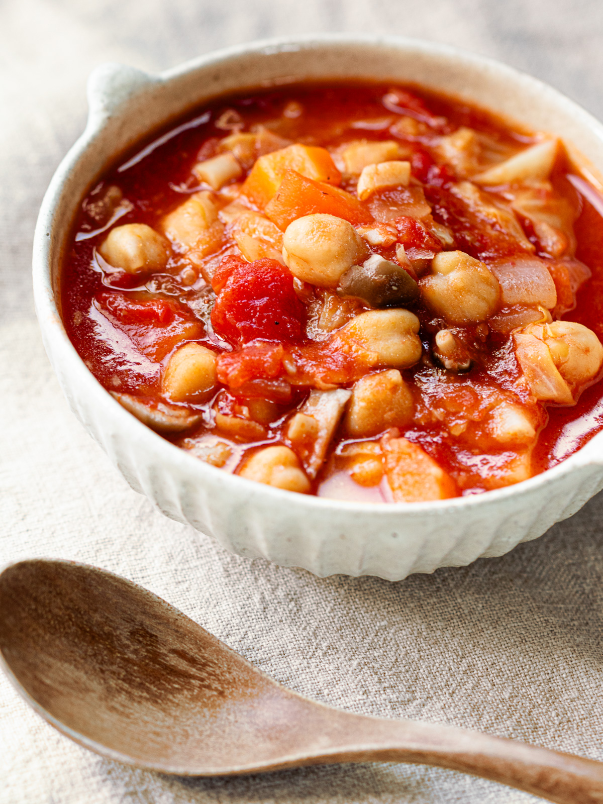 A bowl of chickpea minestrone (vegan pork bean style) with a lot of veggies, bright red color is very appetizing.