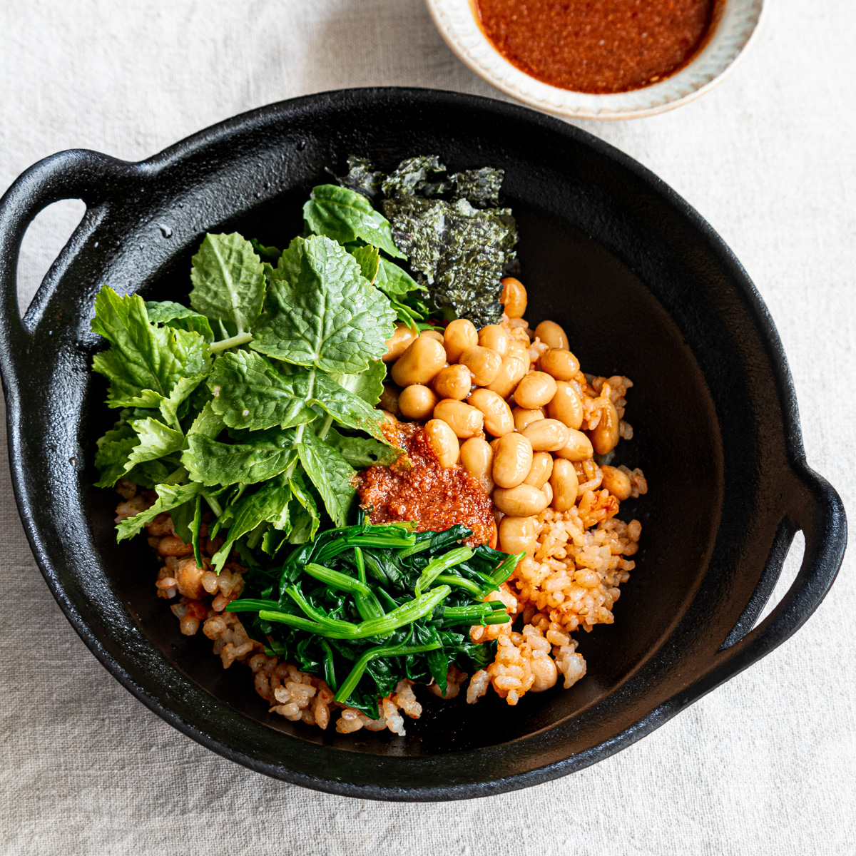 Vegan bibimbap with vegetables and plant-based protein, drizzled with mild soy and gochujang bibimbap sauce