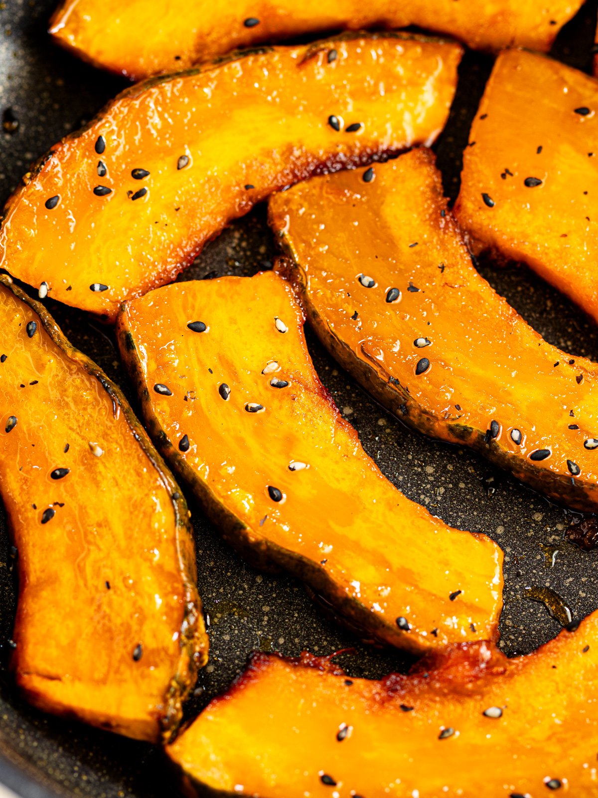 Candied kabocha well-coated with glossy maple-soy glaze in frying pan