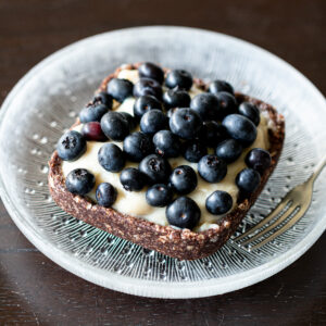 Vegan no-bake blueberry tart with kudzu custard and oatmeal crust, served on a plate