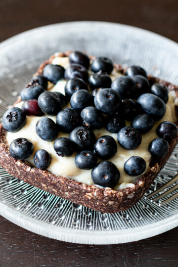 Vegan no-bake blueberry tart with kudzu custard and oatmeal crust, served on a plate
