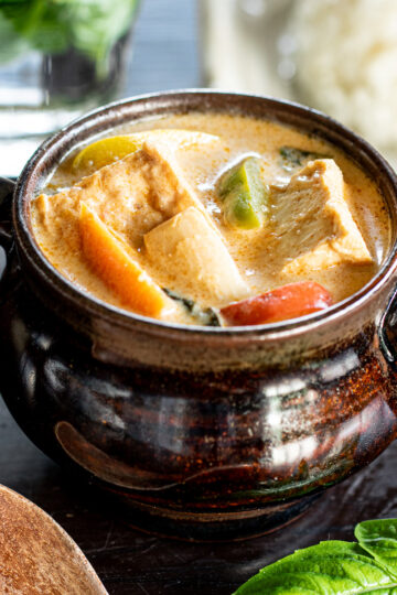 Creamy vegan red curry made without curry paste, showing colorful paprika, eringi mushrooms, and golden cubes of atsuage in coconut-based broth, served with rice.