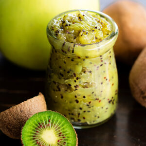 Homemade apple and kiwi jam in glass jar with fresh kiwis and apples