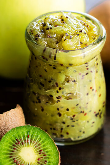 Homemade apple and kiwi jam in glass jar with fresh kiwis and apples