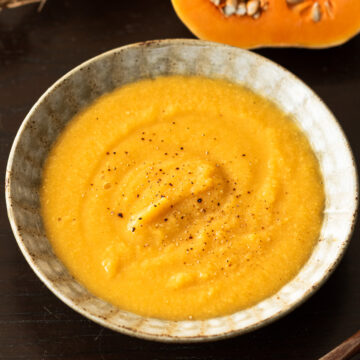Creamy vegan butternut squash and chickpea soup served in a bowl, topped with black pepper