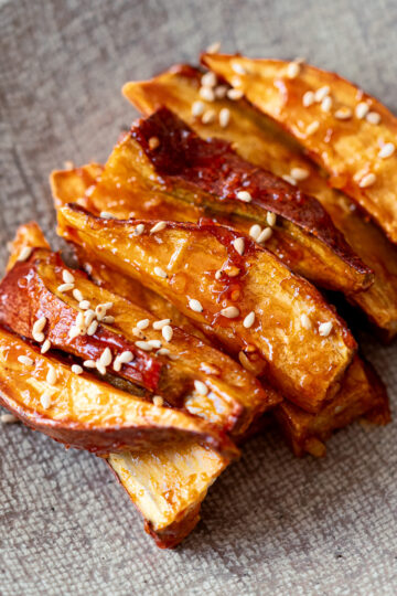 Toaster oven roasted sweet potato sticks coated in sweet and spicy Yangnyeom sauce, a Korean-inspired vegan snack.