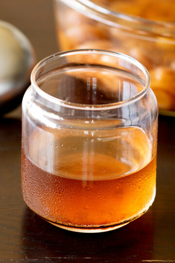 Homemade ume plum vinegar in a glass jar — clear and pale orange yellow