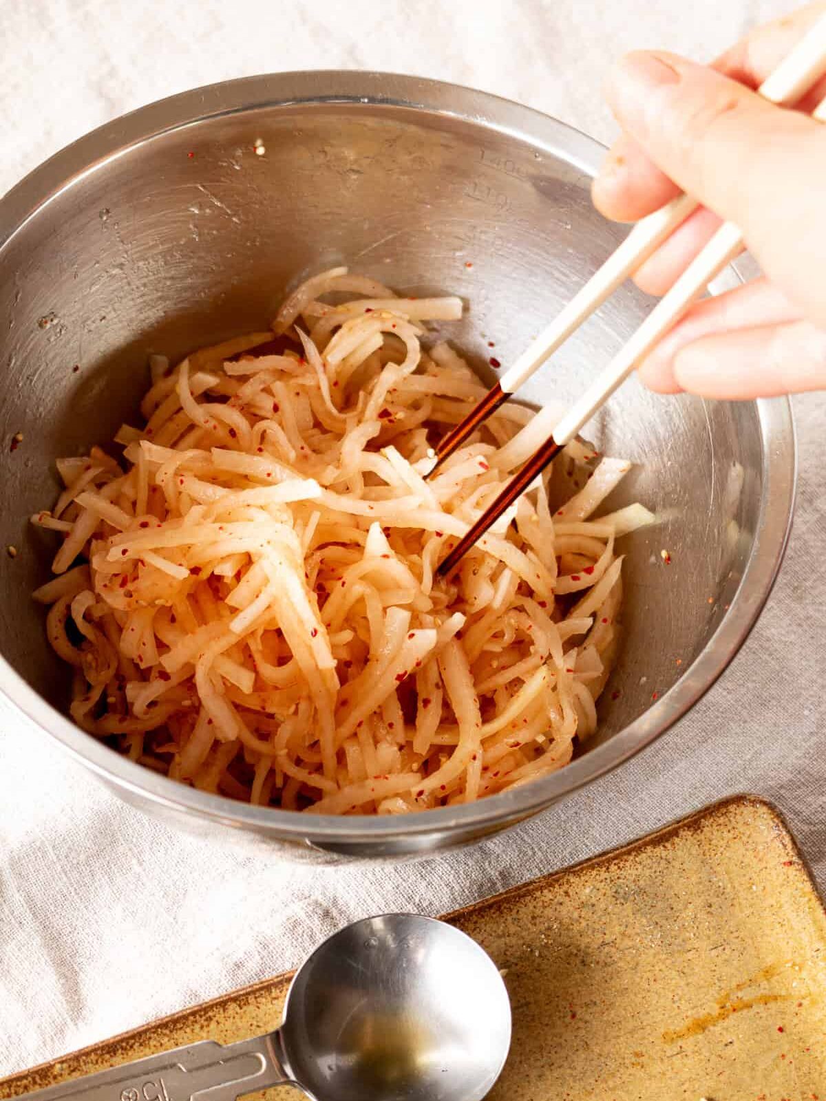 塩もみした大根と調味料を和えている