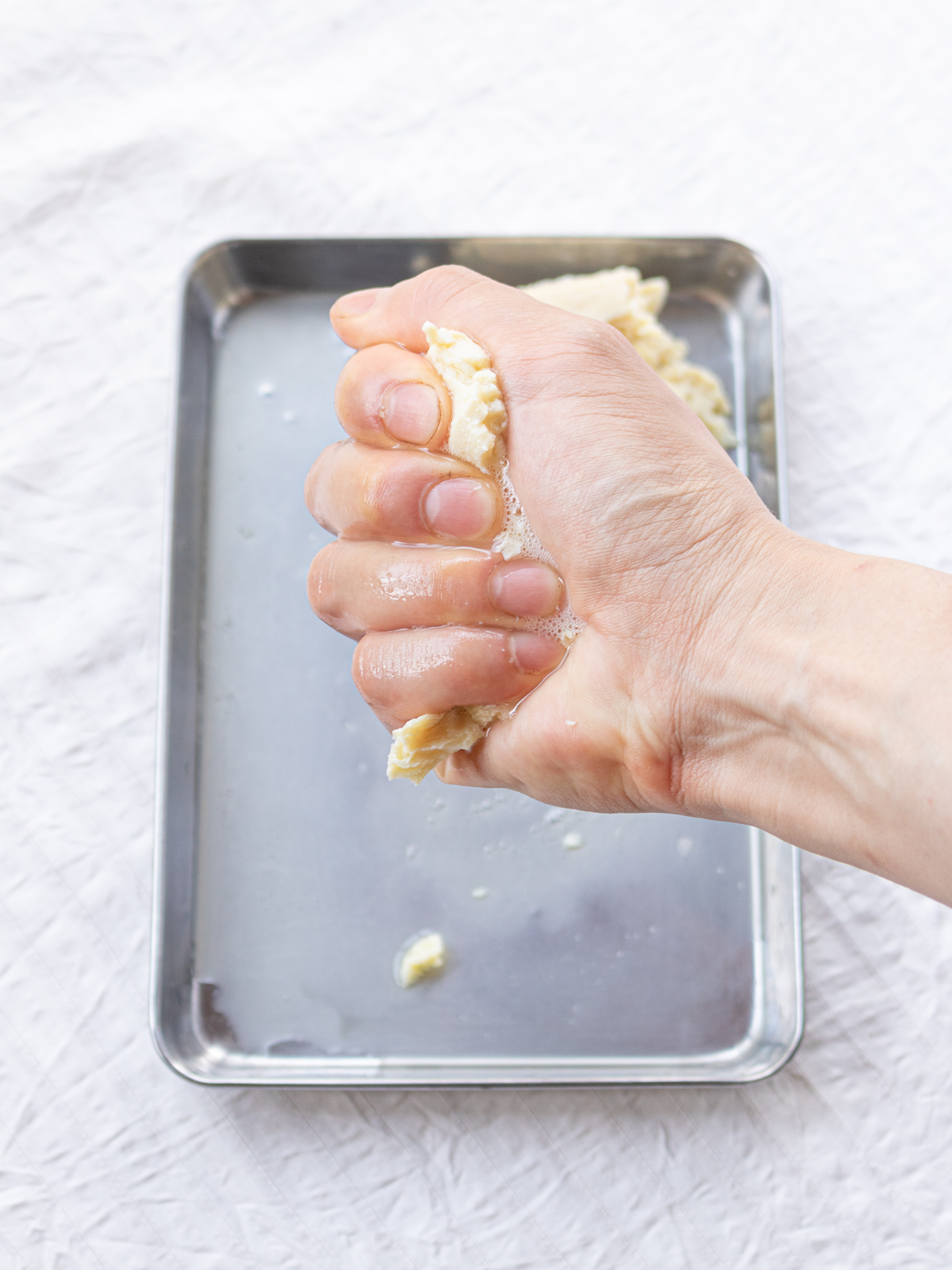 手で握るようにして水気を絞っている冷凍木綿豆腐