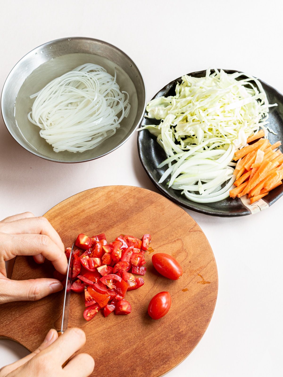 水に浸した米麺と、千切りにした野菜と角切りにしているミニトマト