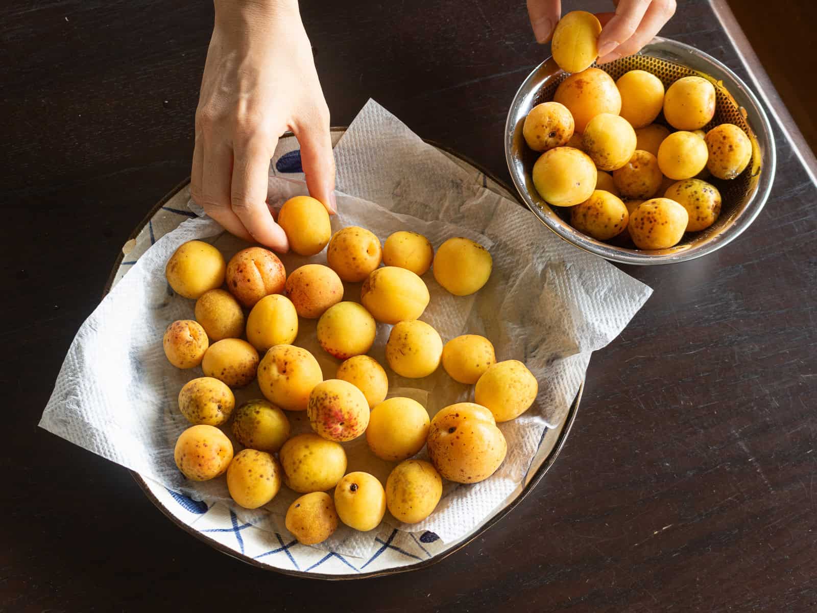 ざるにあけて、キッチンペーパーで水気を切った完熟梅。表面をよく乾かす。