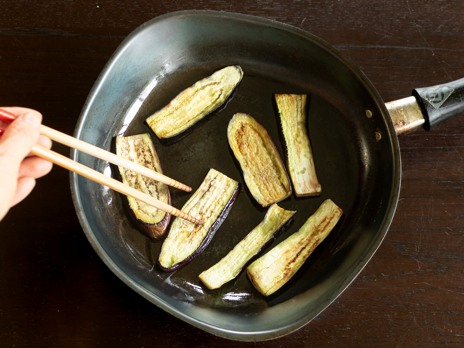 スライスしたナスをフライパンで焼いている様子