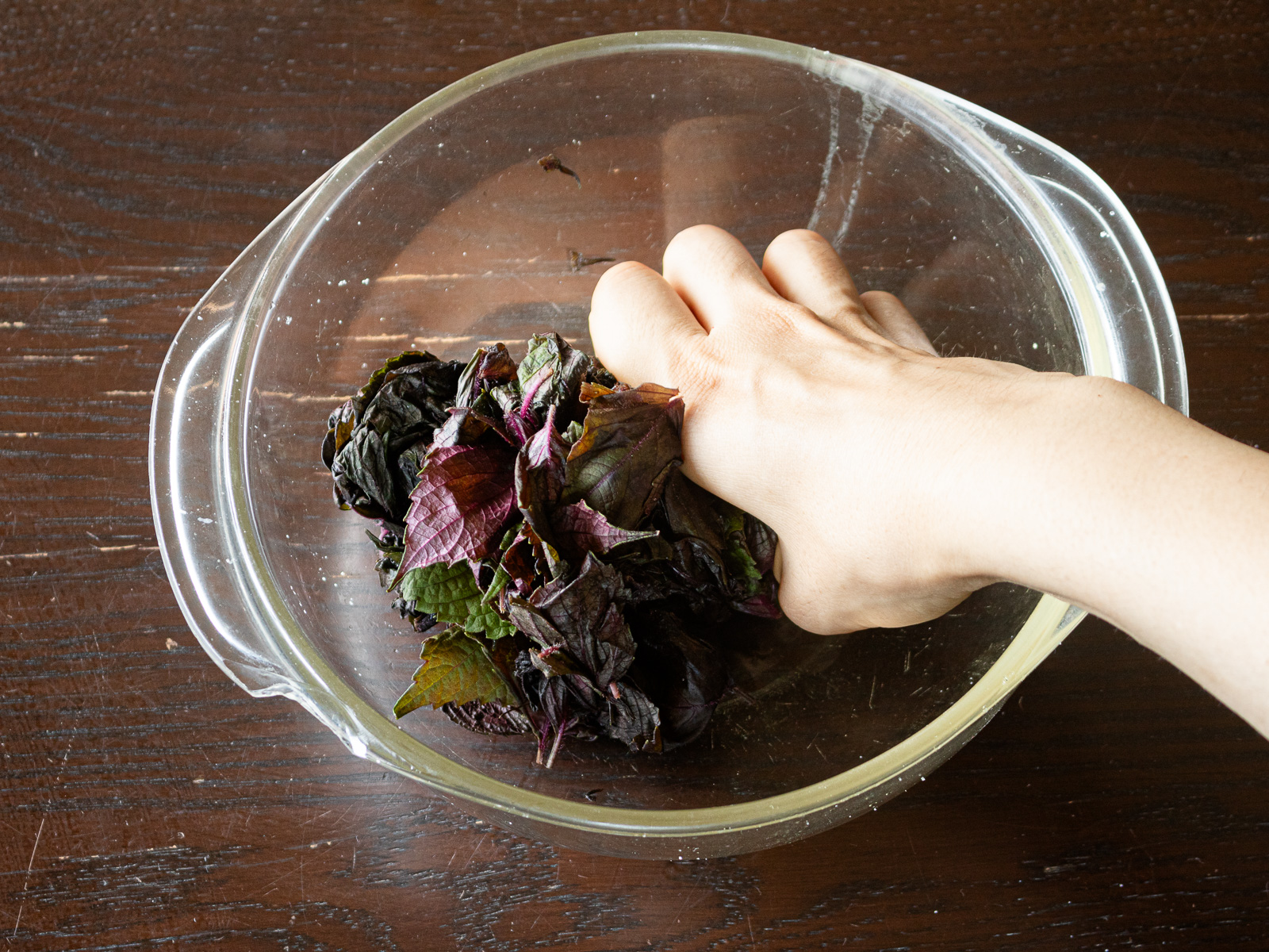 Massaging salted red shiso leaves until dark purplish juice is released.
