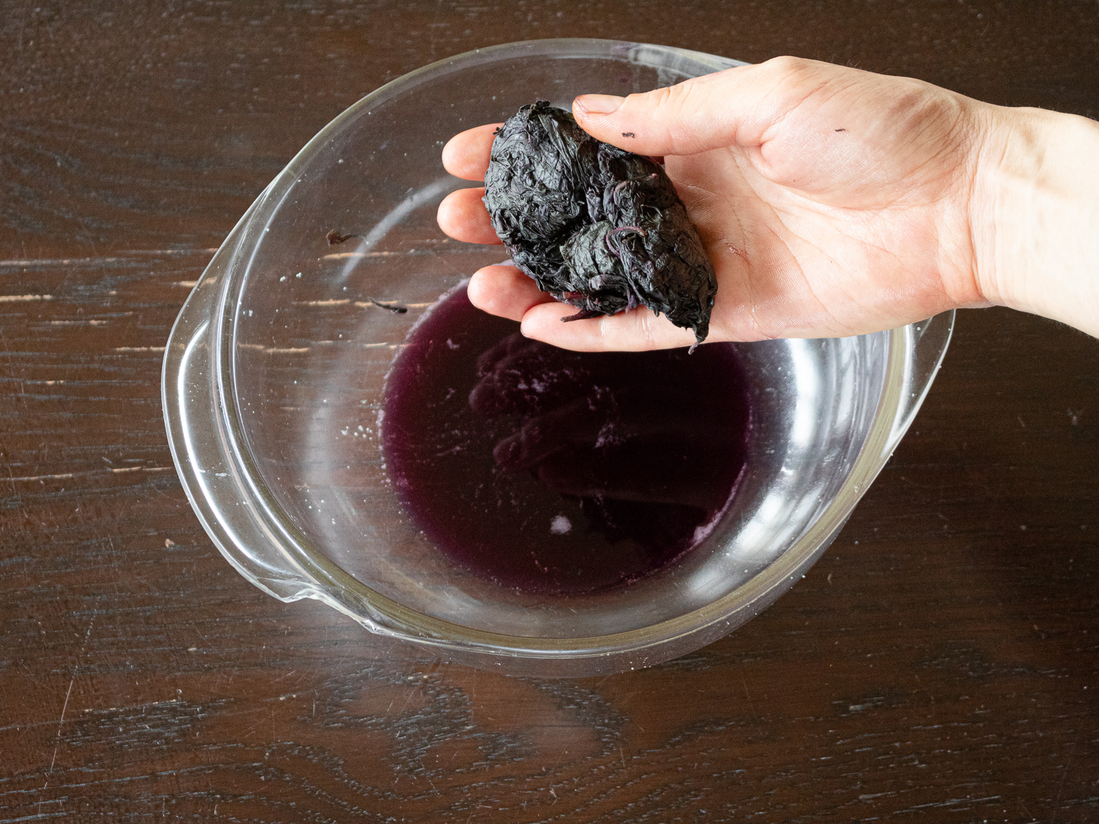 Squeezing massaged red shiso leaves and discarding the extracted liquid.