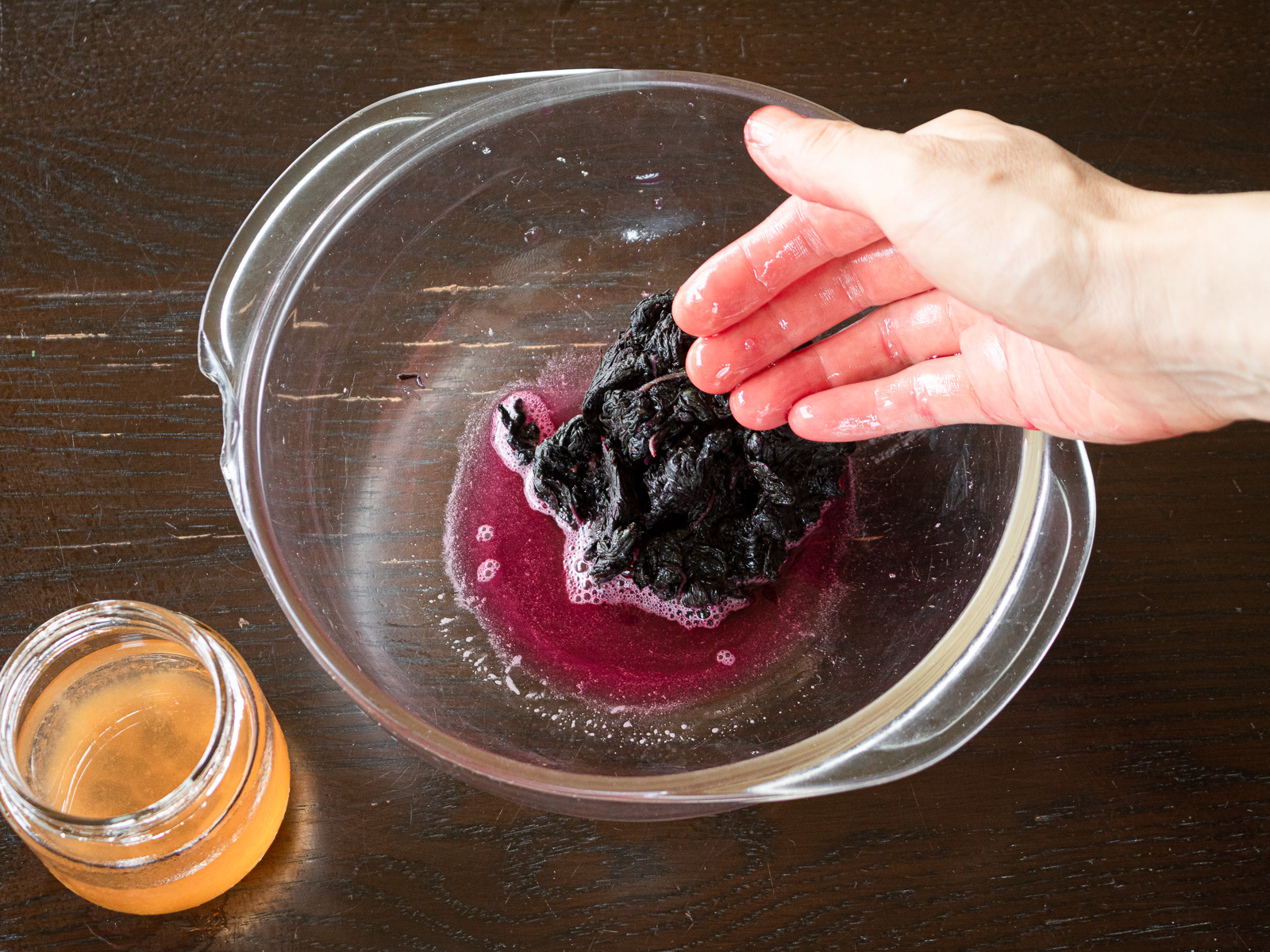 Adding ume vinegar to well-massaged red shiso leaves and gently massaging until evenly coated; leaves turn a vibrant pink.