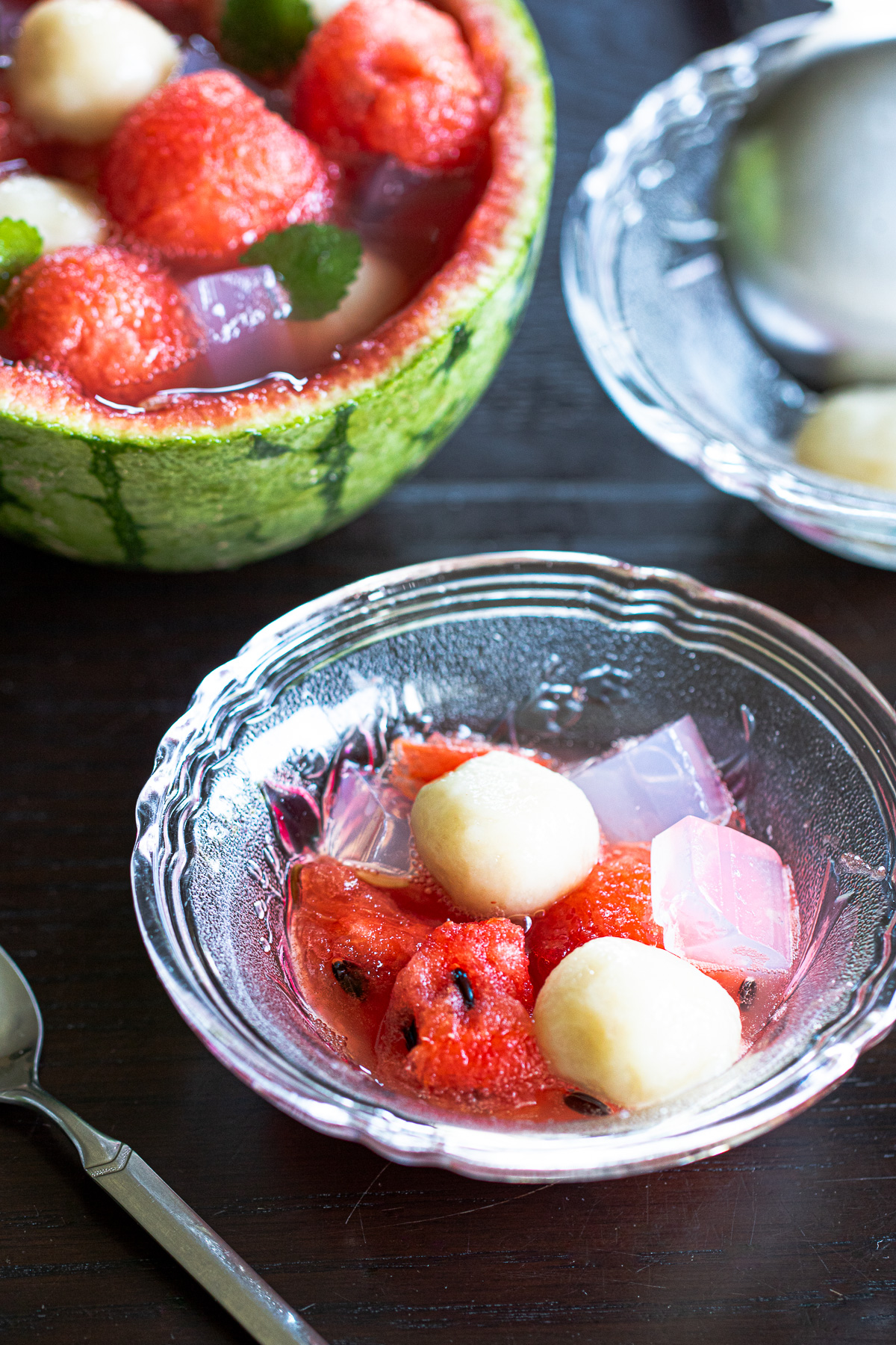 Single-serving vegan summer dessert: watermelon fruit punch with chewy banana mochi and pink agar jelly.