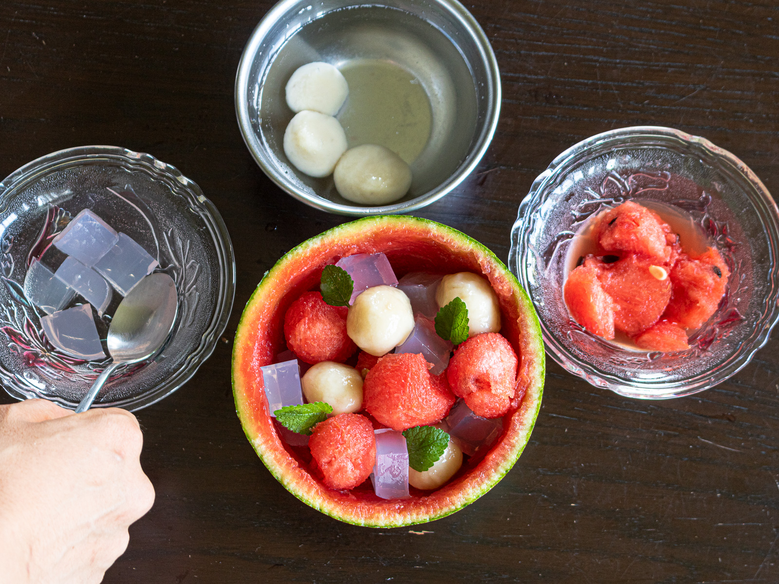 Assemble vegan watermelon fruit punch with watermelon balls, banana mochi dumplings, pink agar jelly cubes, and fresh mint in a hollowed watermelon bowl