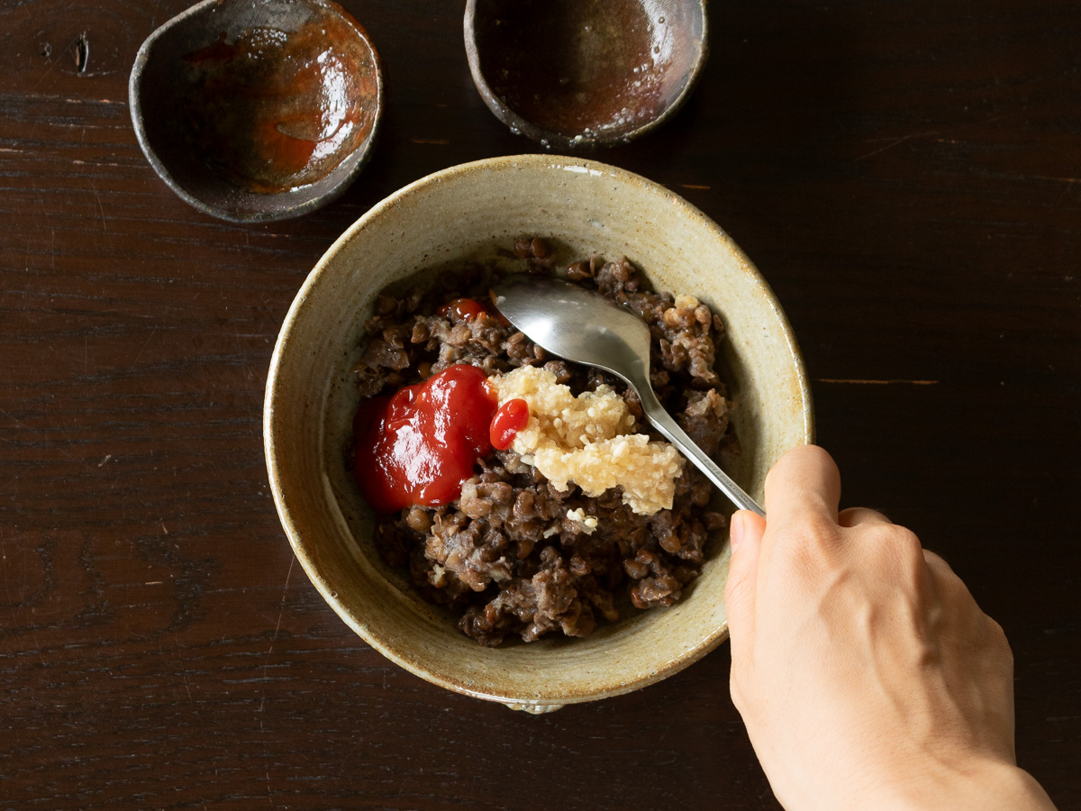 ボウルで茹でた皮付きレンズ豆、玉ねぎ麹、ケチャップを混ぜる様子。簡単ヴィーガンピーマン肉詰め風の準備中。