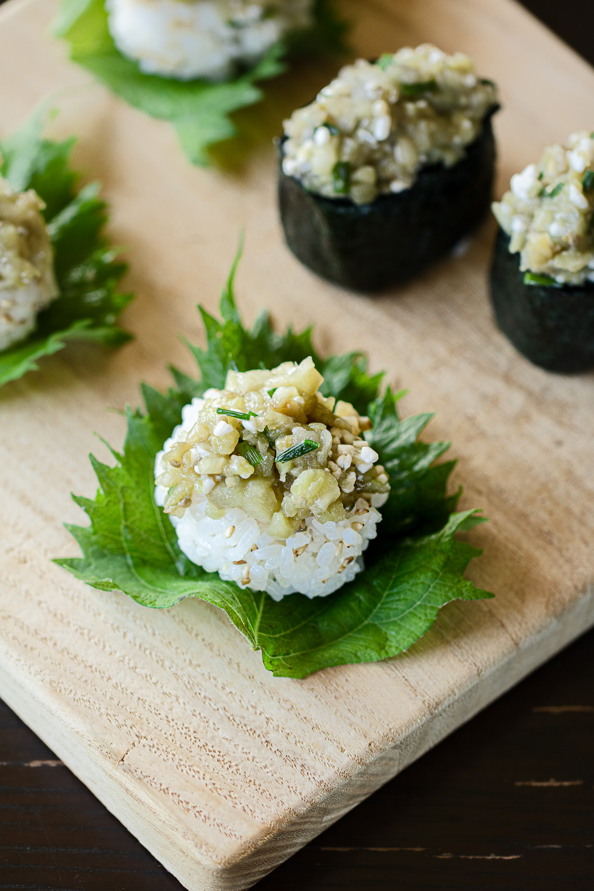 Vegan gunkan sushi platter with steamed eggplant and koji, served on wooden board