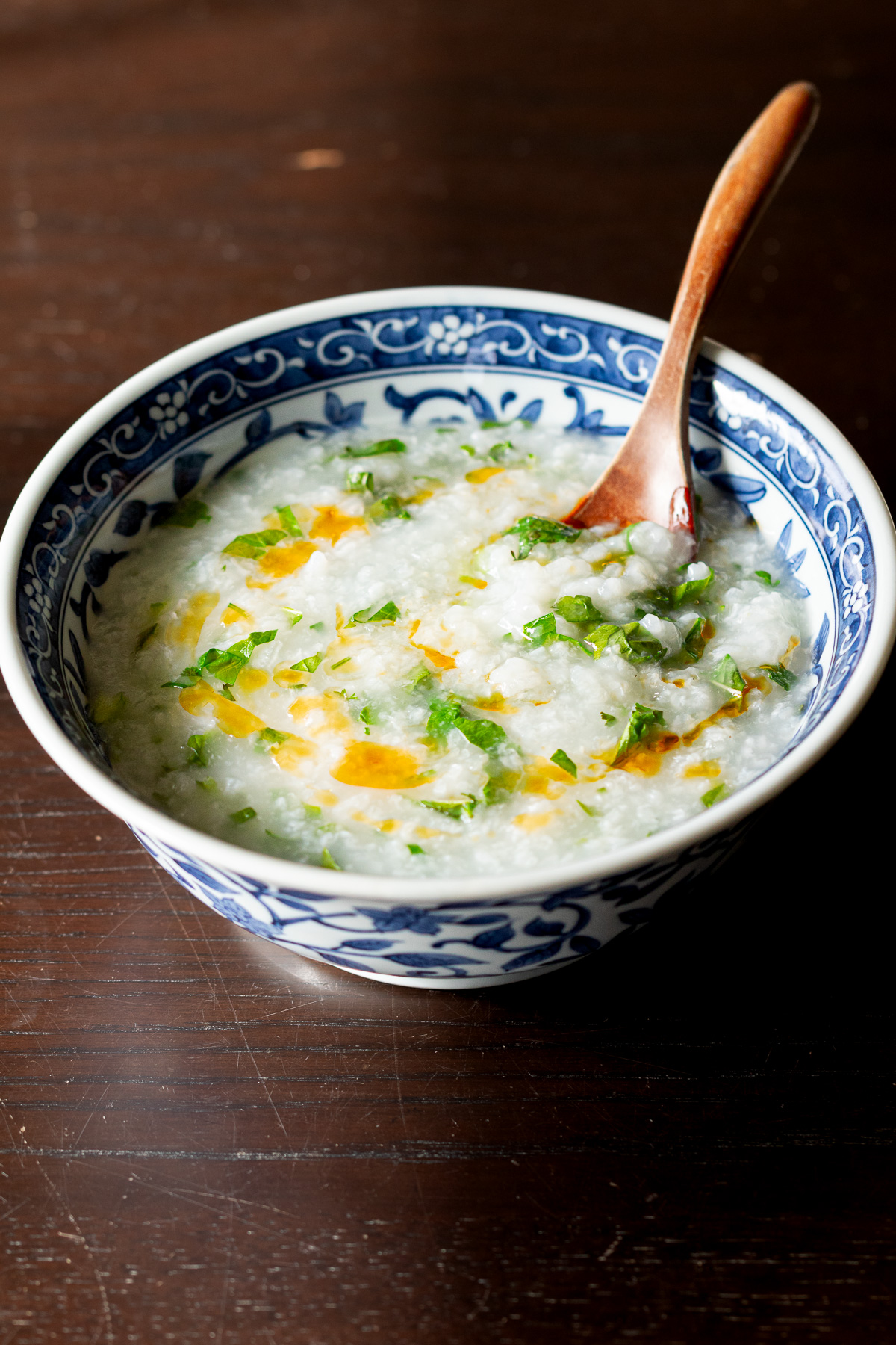 ヴィーガン アジア風朝粥 - 大根とカブの葉、香菜、ラー油をトッピングした青い器のお粥