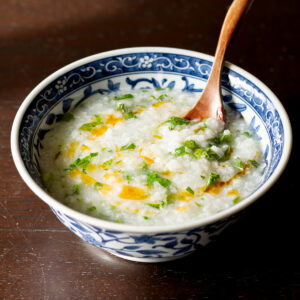 ヴィーガン アジア風朝粥 - 大根とカブの葉、香菜、ラー油をトッピングした青い器の簡単お粥