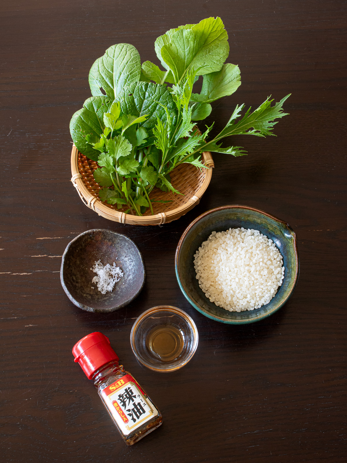 朝粥の材料一式 - 白米、大根の葉、カブの葉、水菜、小松菜、香菜、ラー油、塩