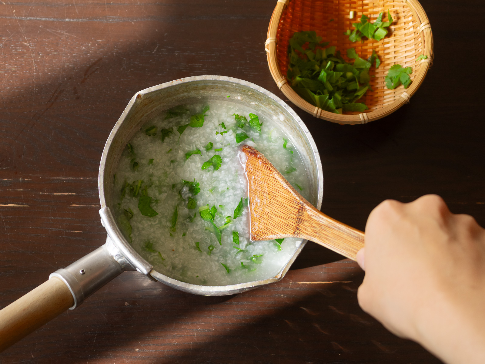 鍋でお粥を煮る - 葉野菜の茎を加えて軽く火を通している様子