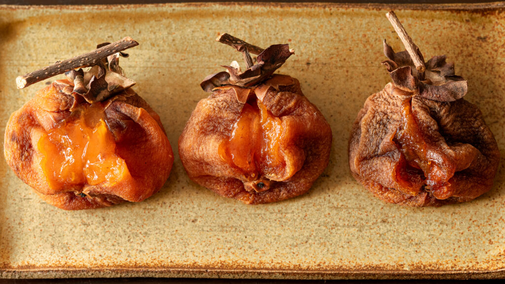 三つの干し柿の仕上がり別。左は水分が多く果肉がとろり。右はねっとりした果肉、真ん中はその中間