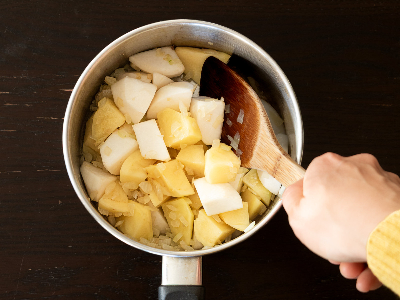 鍋にカブとジャガイモを加えて炒めている様子