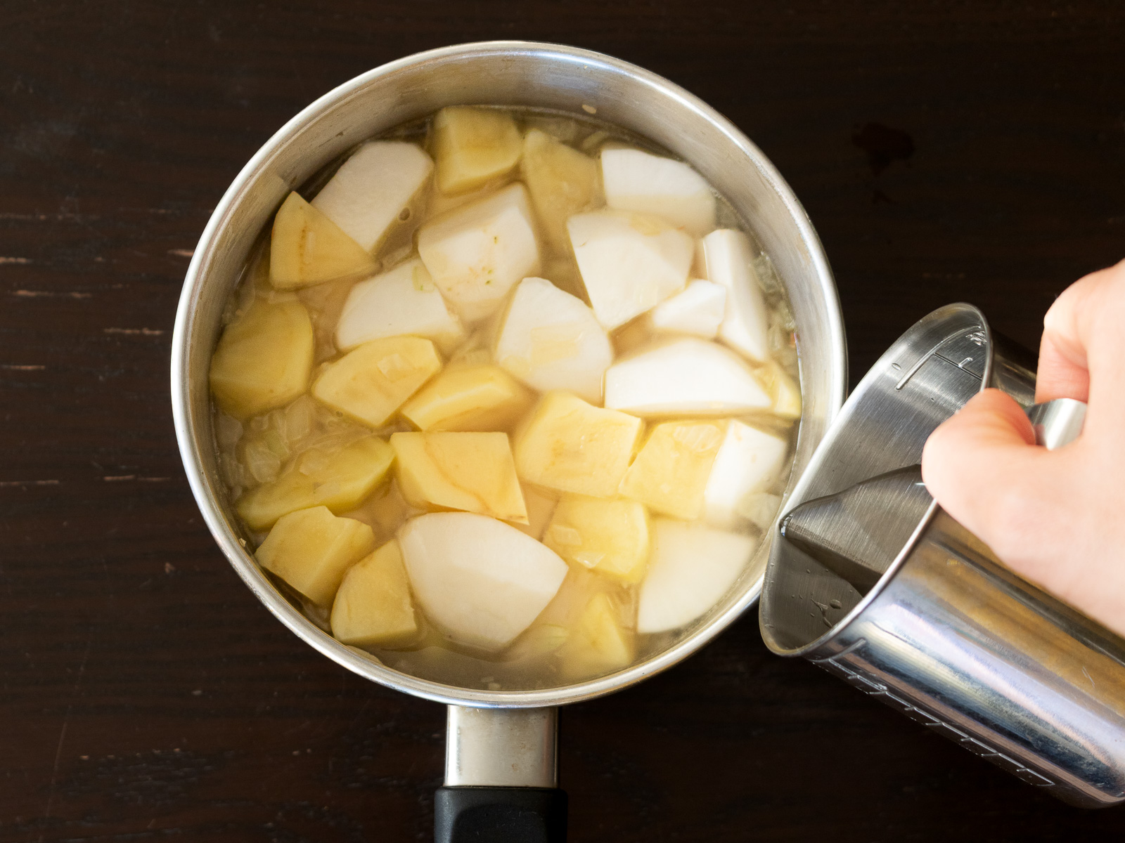 鍋で煮込まれるカブとジャガイモ