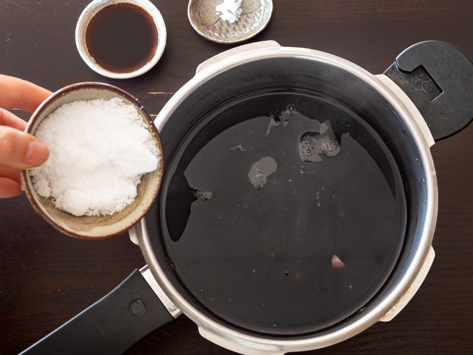下茹でした黒豆に砂糖と醤油を加えて味付けしている様子