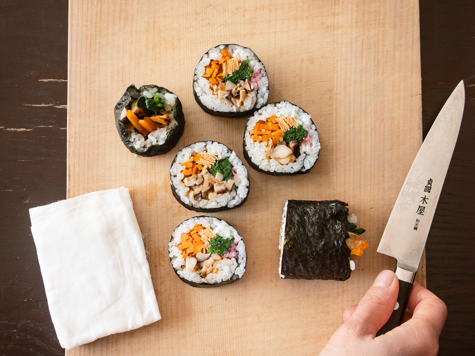 湿らせた布で包丁を拭きながら、太巻きをカットしている工程