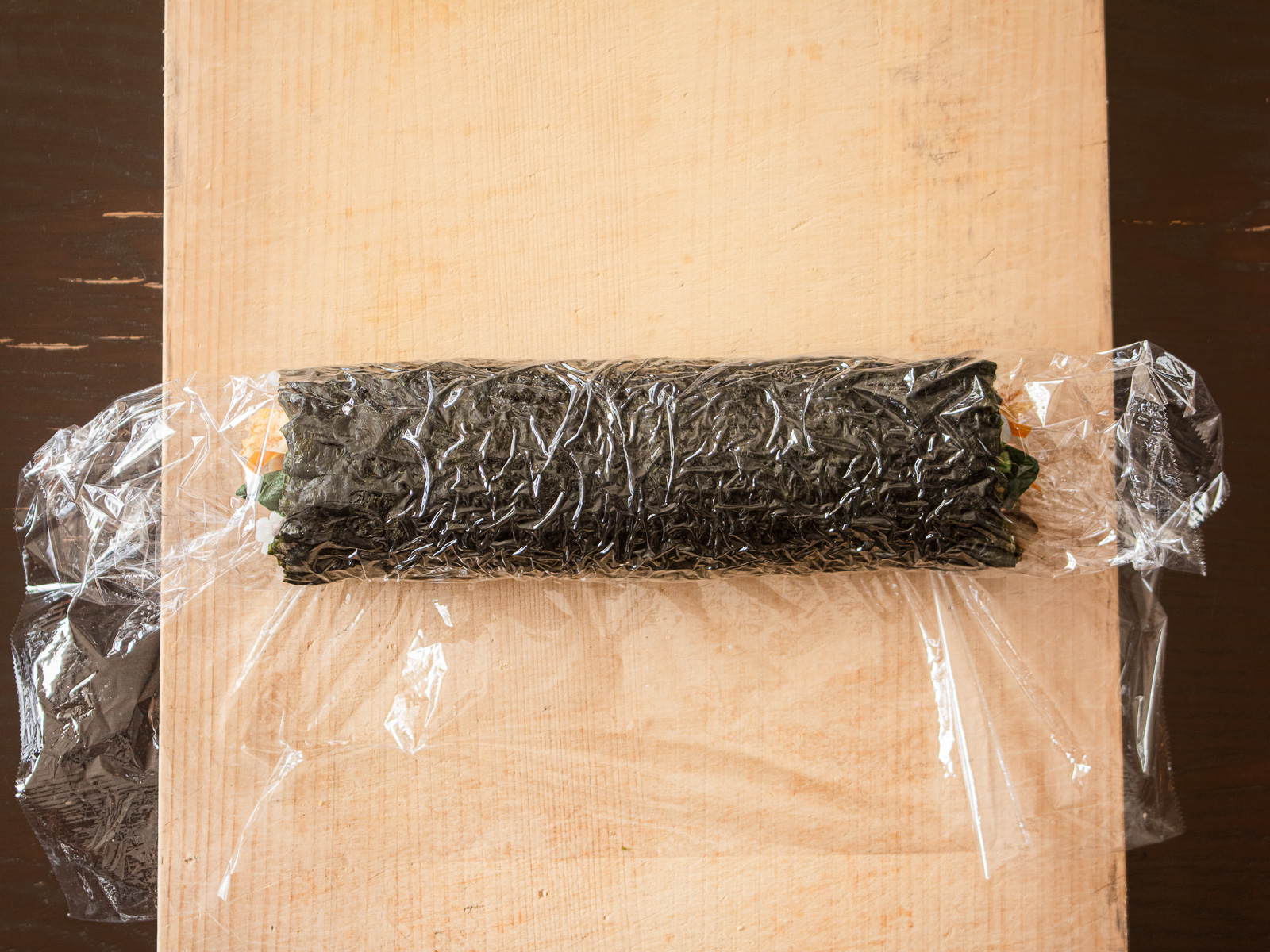 巻き終わった太巻きをラップに包み、切る前に少し休ませている様子
