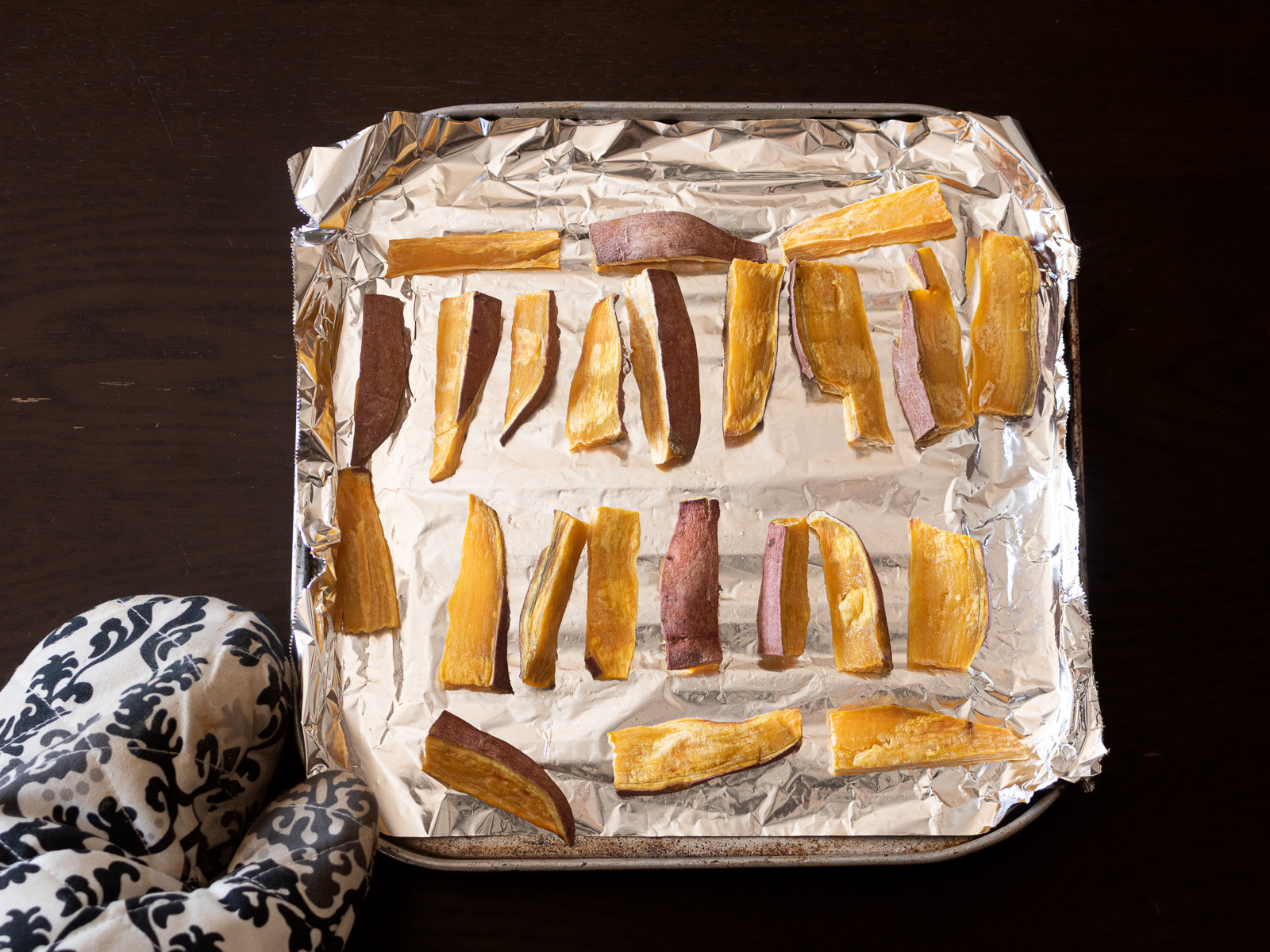 アルミホイルに並べたスティック状のさつまいもをトースターで焼く工程