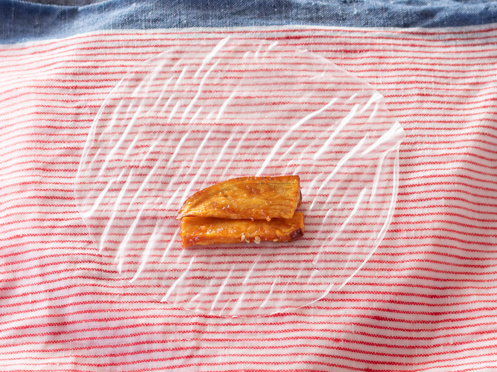 ライスペーパーの上にべにはるかのヤンニョムスティックを置く。生春巻きの巻き方、具材を並べる最初のステップ